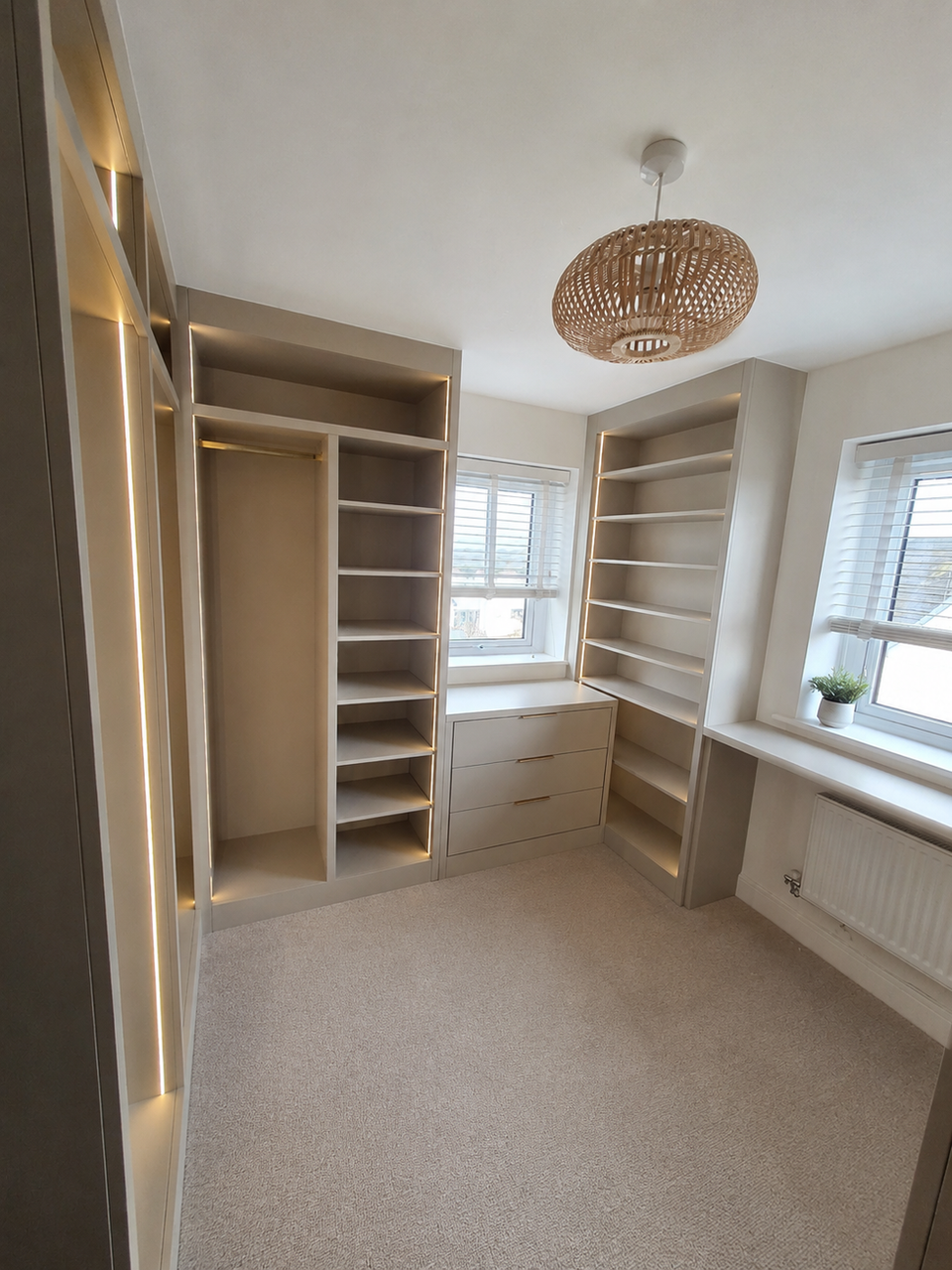 Fitted walk-in wardrobe with warm lighting by Beckinsale UK